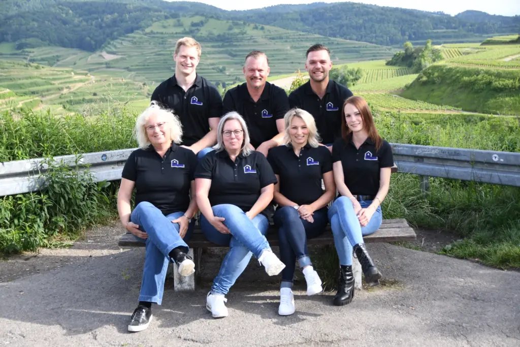 Gruppenfoto vom Team der K&G Wohnbau GmbH in Vogtsburg mit Geschaeftsfuehrer Adrian Guetermann mit dem Kaiserstuhl im Hintergrund